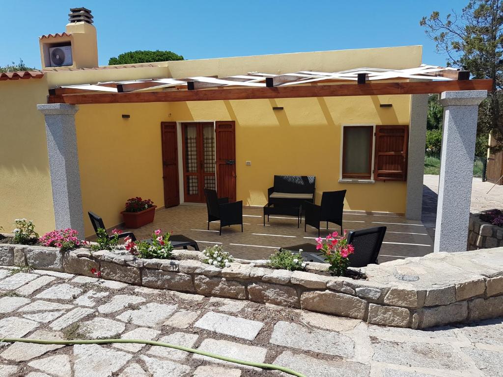 un patio con sillas negras y una casa amarilla en Cottage Vacanze La Maddalena en La Maddalena