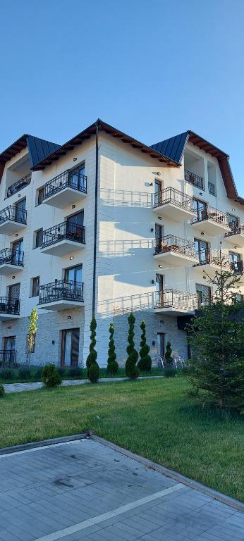 - un grand immeuble blanc avec un parking dans l'établissement Apartman Aura Hills Zlatibor, à Zlatibor