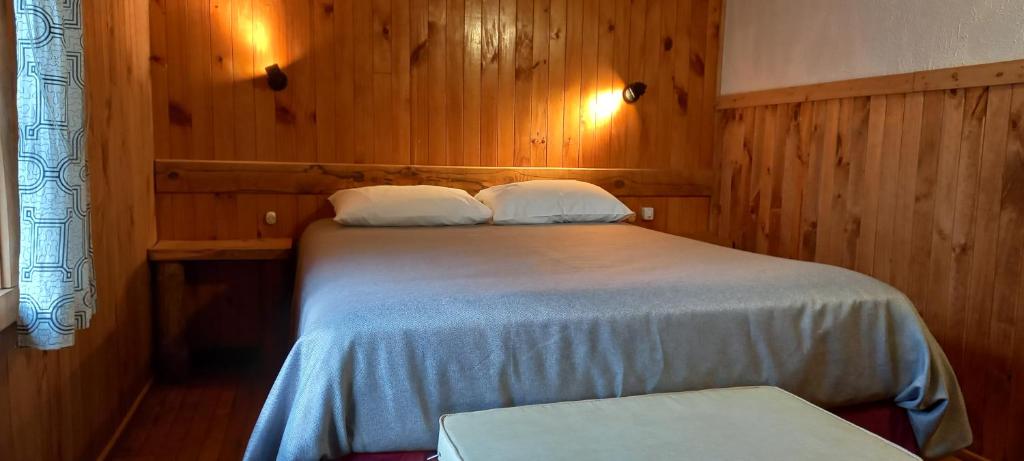 um quarto com uma cama com lençóis brancos e paredes de madeira em Cabañas Turin em Puerto Puyuhuapi