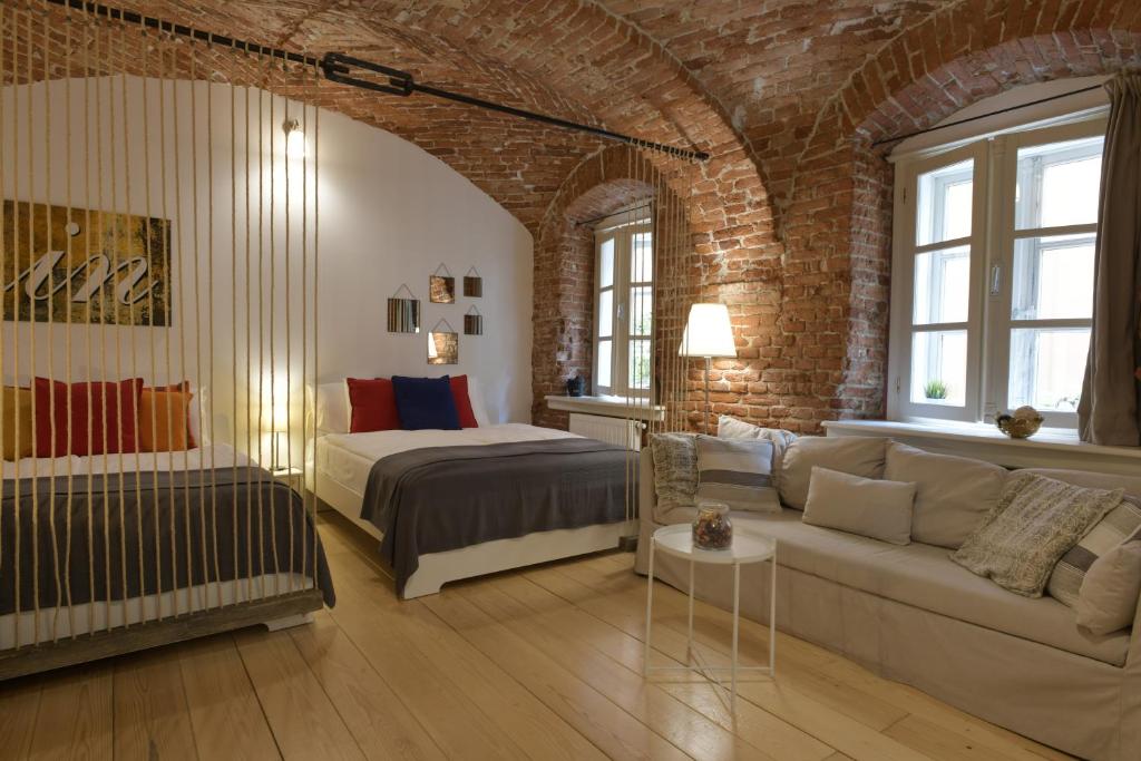 a bedroom with a bed and a couch and a brick wall at Apartment Azalea in Zagreb