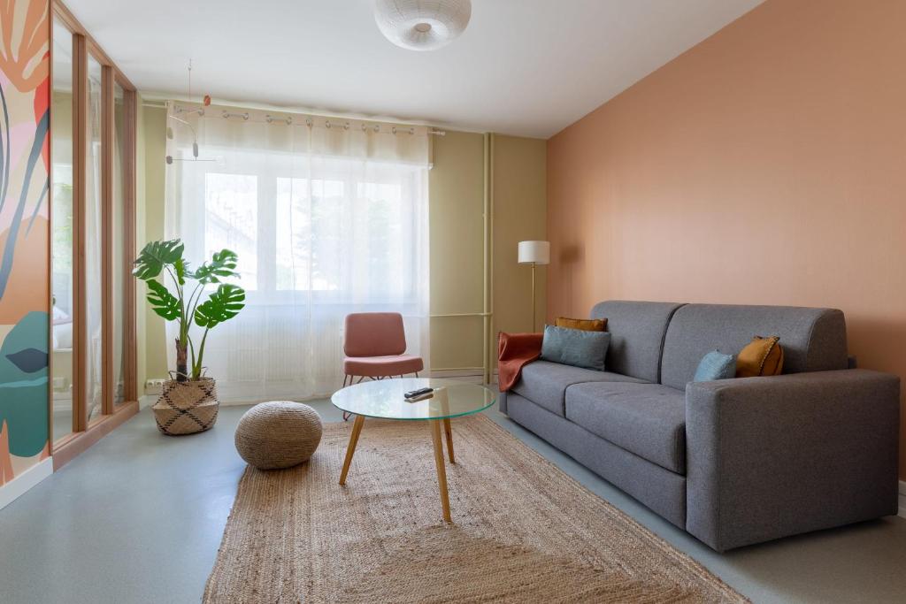 ein Wohnzimmer mit Sofa und Tisch in der Unterkunft Travel Homes - Le Freedom, chaleureux & spacieux in Mulhouse