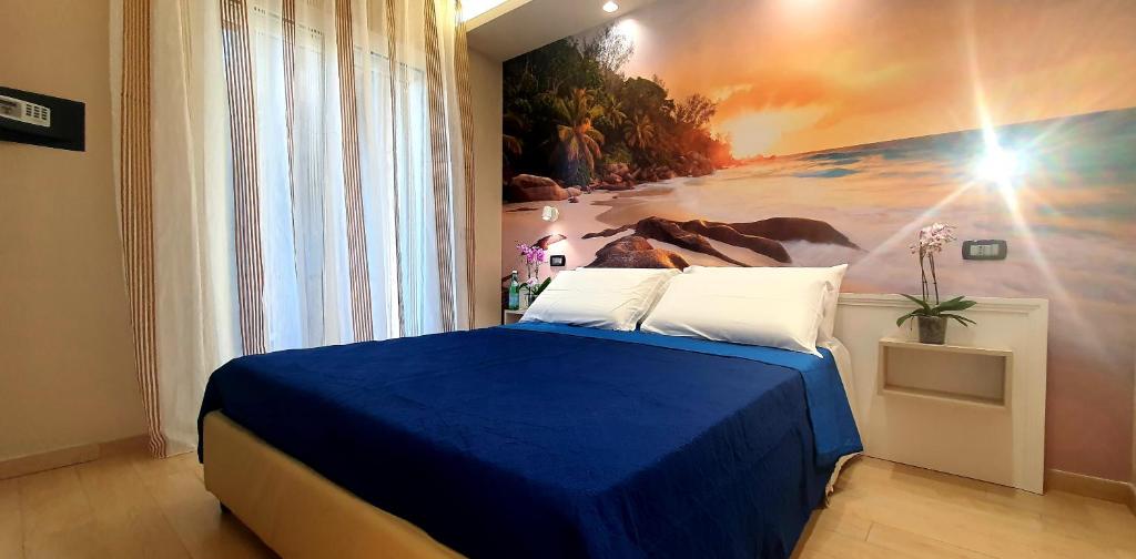 a bedroom with a blue bed with a painting on the wall at Grillo Superior Apartments - Enjoy Your Life! in Capo Vaticano