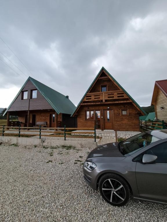 une voiture garée devant certains bâtiments en bois dans l'établissement Original Wooden Lodge 2, à Žabljak