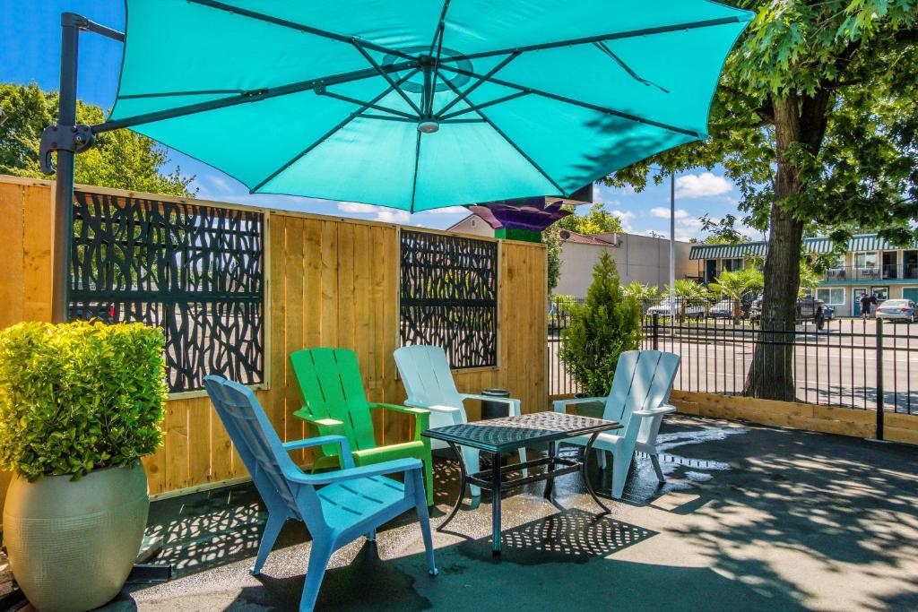 a patio with chairs and a table with a blue umbrella at Signature Inn Eugene in Eugene