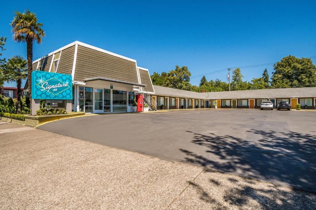 a large building with a parking lot in front of it at Signature Inn Eugene in Eugene