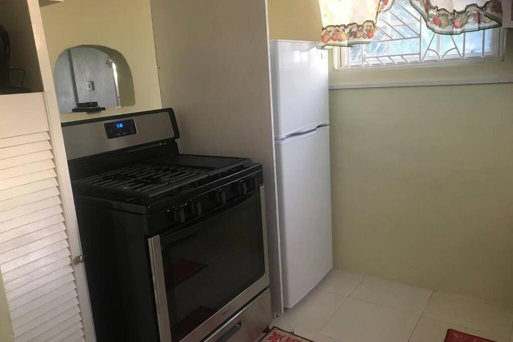 a small kitchen with a stove and a refrigerator at Sasha’s Holiday Home Oistins Barbados in Christ Church
