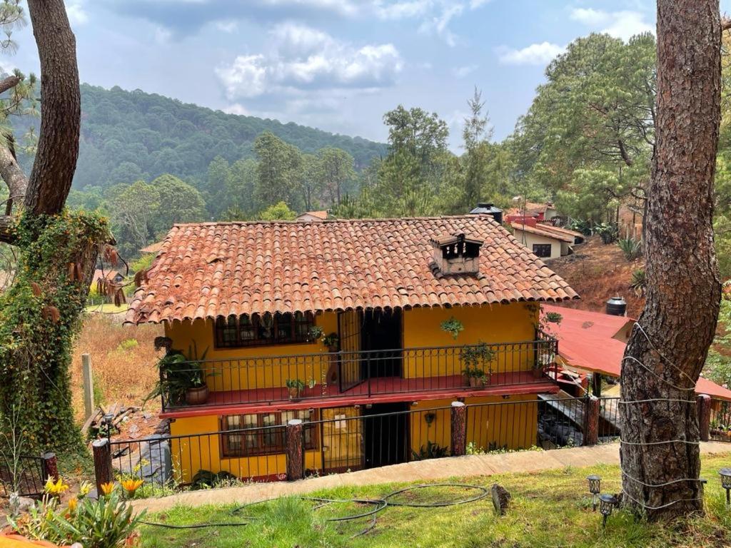 una casa amarilla con techo rojo en Cabañas Yasmina, en Mazamitla