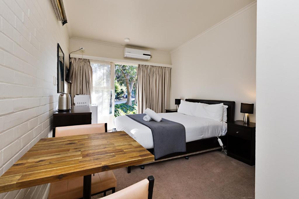 a bedroom with a bed and a wooden table at Gardenview in Wangaratta