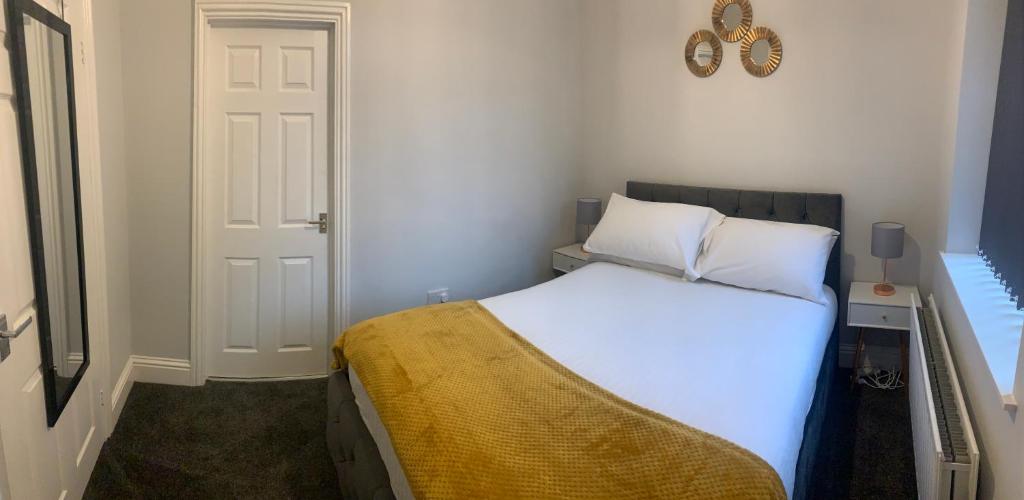 Un dormitorio con una cama blanca con una manta amarilla. en Gateshead Serviced Apartment Ideal for Contractors and Vacationing, en Gateshead