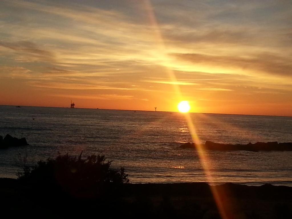 a sunset over the ocean with a lighthouse in the distance at Il Girasole in Crotone