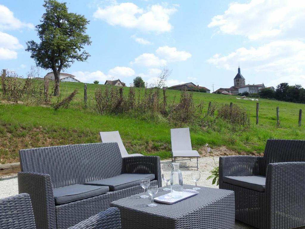 eine Terrasse mit einem Tisch, Stühlen und einem Feld in der Unterkunft Gîte Dommartin-le-Franc, 3 pièces, 4 personnes - FR-1-611-64 