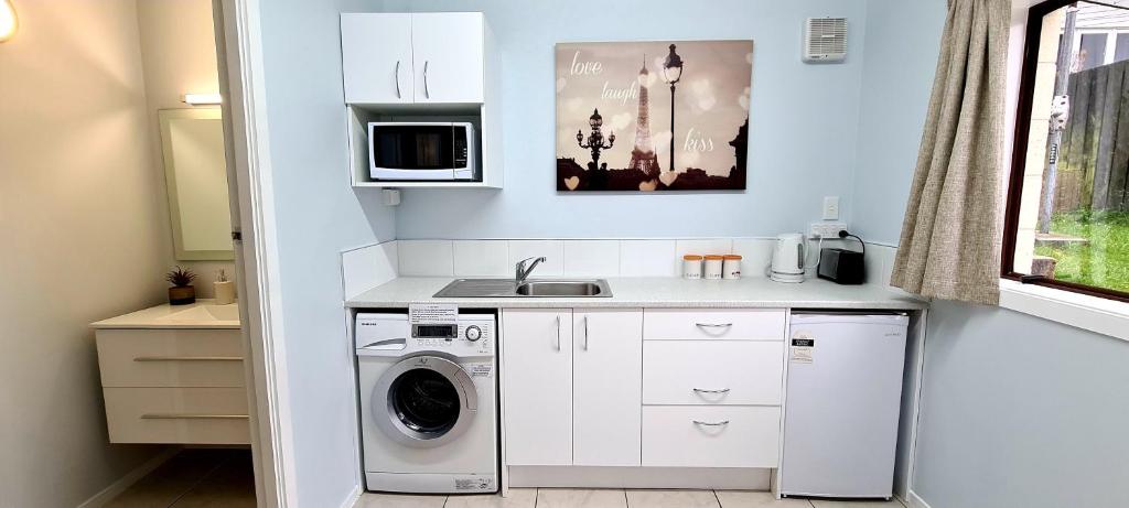 a small kitchen with a washing machine and a sink at Beautiful Panoramic views in Dunedin
