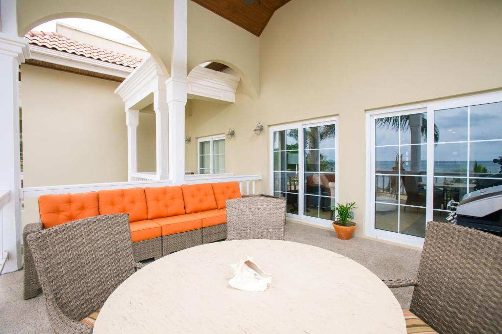 eine Terrasse mit einem orangefarbenen Sofa sowie einem Tisch und Stühlen in der Unterkunft Lawson Rock - Angelfish 203 Condo in Sandy Bay
