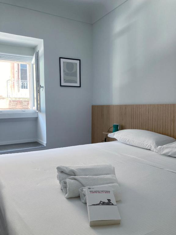 een wit bed met een boek erop bij Sognalibro Bed and Books in Ragusa