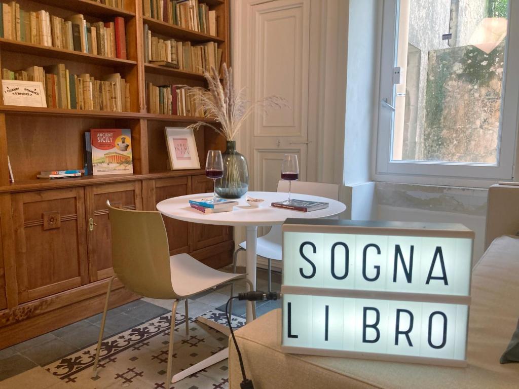 een tafel en stoelen in een kamer met een boekenplank bij Sognalibro Bed and Books in Ragusa