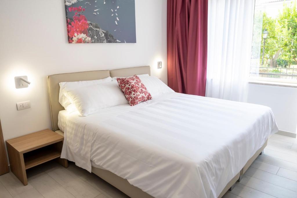 a white bed with a red pillow on it in a bedroom at Casa Marino in Sorrento