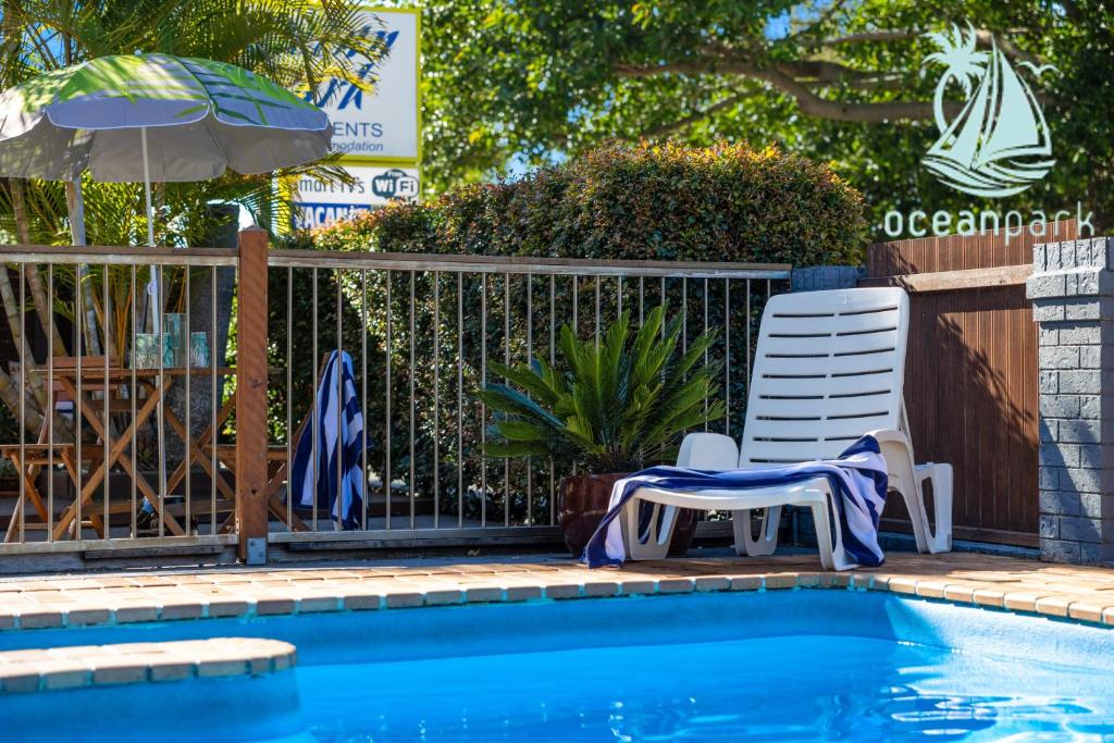 a swimming pool with a chair and an umbrella at Ocean Park Motel & Holiday Apartments in Coffs Harbour