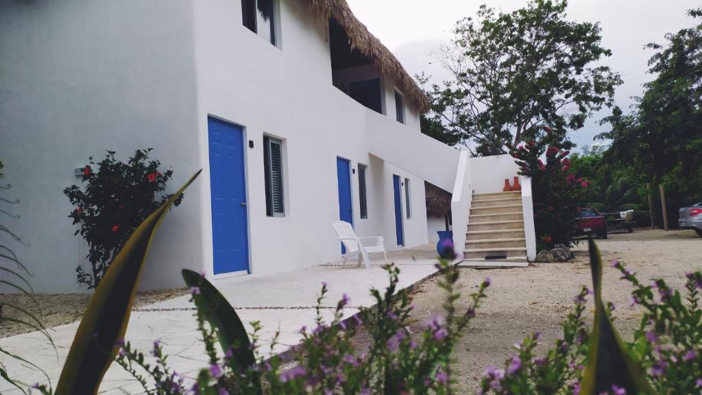 ein weißes Gebäude mit einer blauen Tür und einer Treppe in der Unterkunft Posada Mykonos in Bacalar