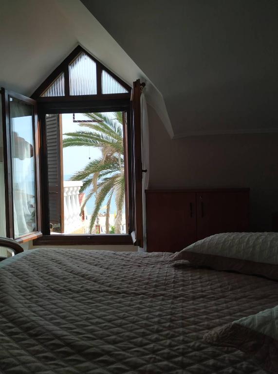 sypialnia z łóżkiem i dużym oknem w obiekcie Palm Garden Villa w mieście Orfánion