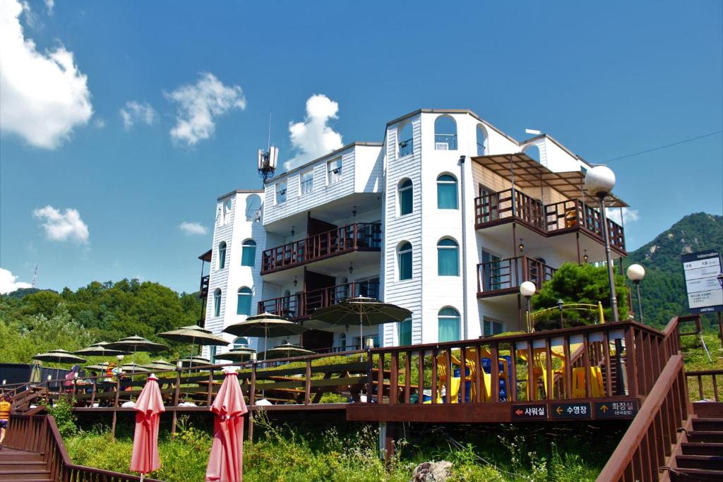 a large white building with umbrellas in front of it at Travely Hotel Gapyeong in Gapyeong