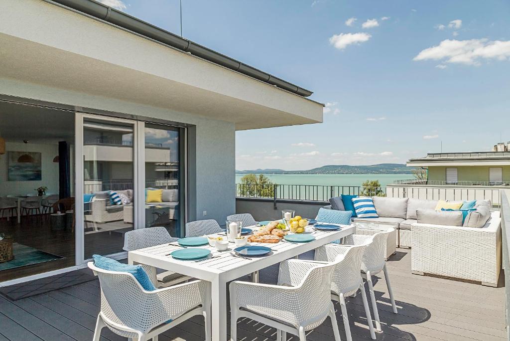 eine Terrasse mit einem Tisch, Stühlen und einem Sofa in der Unterkunft Blue Apartments in Balatonlelle