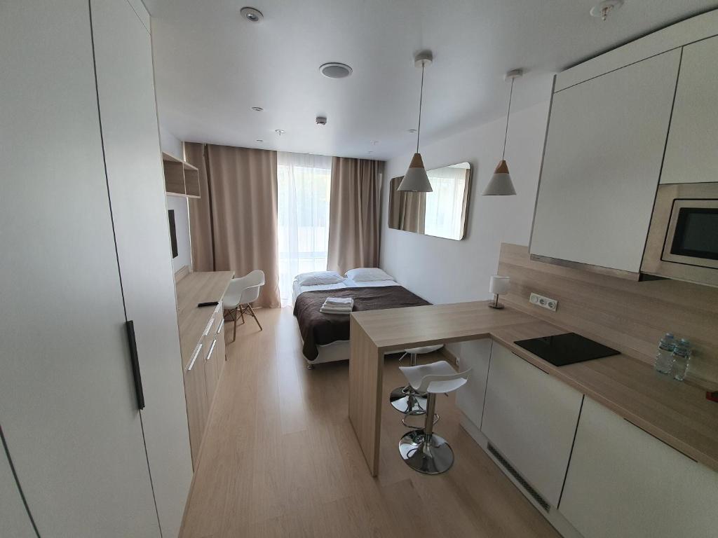 a bedroom with a bed and a kitchen with a desk at Maximus apartments Marata in Saint Petersburg