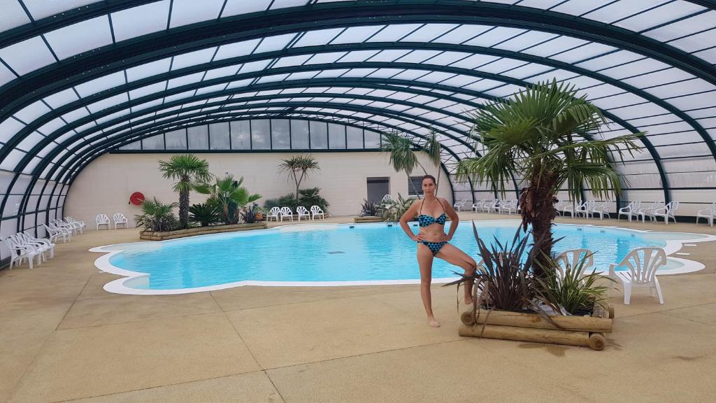 a woman in a bikini standing next to a swimming pool at Normandie Sword Beach in Hermanville-sur-Mer