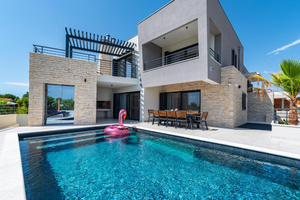 a villa with a swimming pool in front of a house at Villa Roca in Privlaka