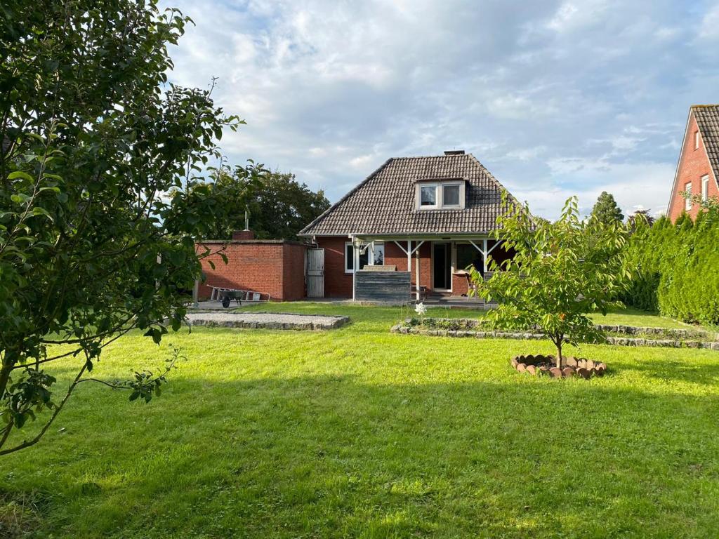 a house in a yard with a green lawn at Ferienhaus Sieglinde mit Deichblick in Emden