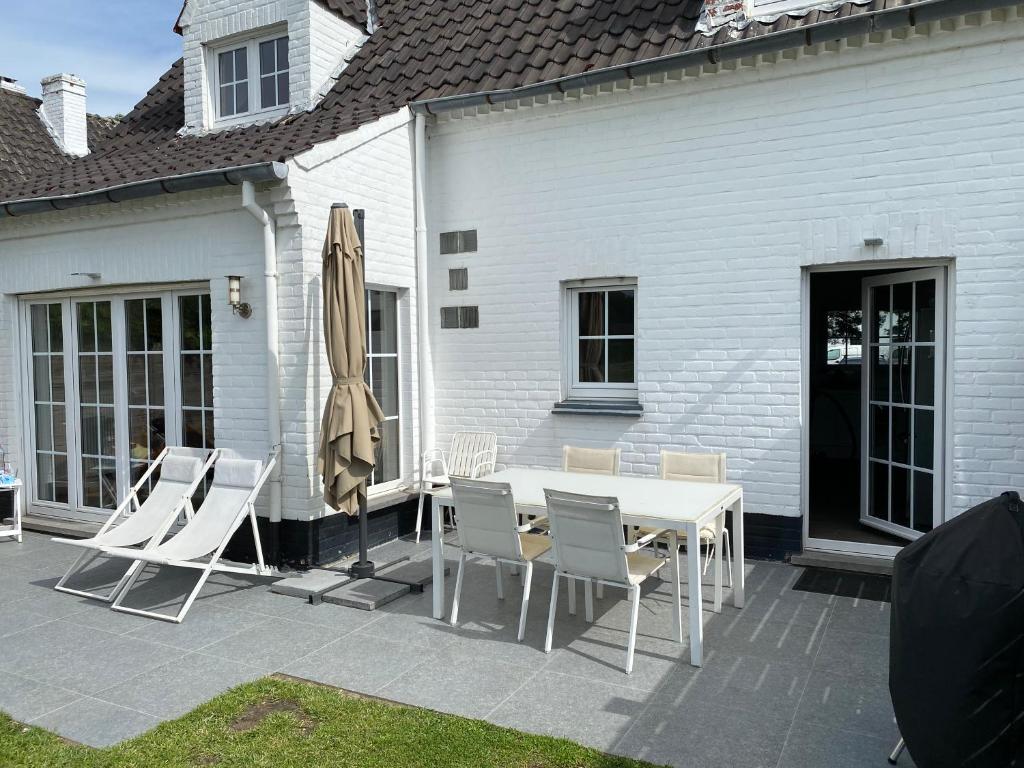 une terrasse avec une table, des chaises et un parasol dans l'établissement Begijnhof 13 Holiday Home, à Zuienkerke