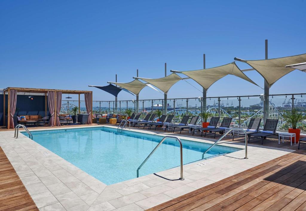 a swimming pool with chairs and umbrellas at Hyatt Centric the Pike Long Beach in Long Beach