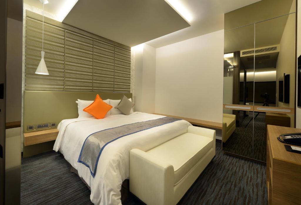 a bedroom with a large white bed with orange pillows at Golden Tulip Glory Fine Hotel in Tainan