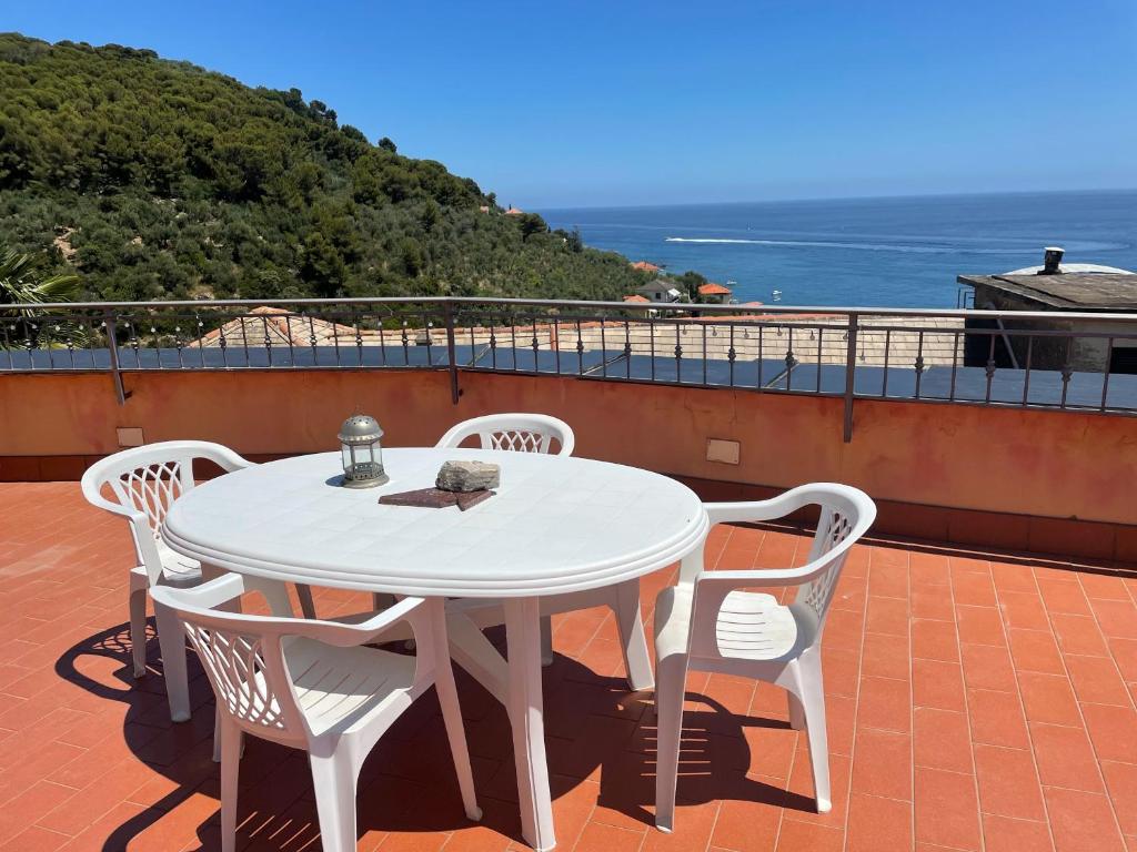 una mesa blanca y sillas en un balcón con vistas al océano en Casa Maria, en Cervo