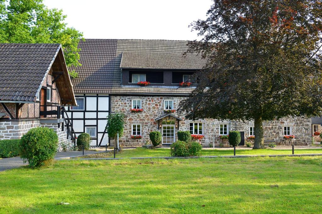 ein großes Steinhaus mit einem Baum davor in der Unterkunft Gut Funkenhof in Sundern