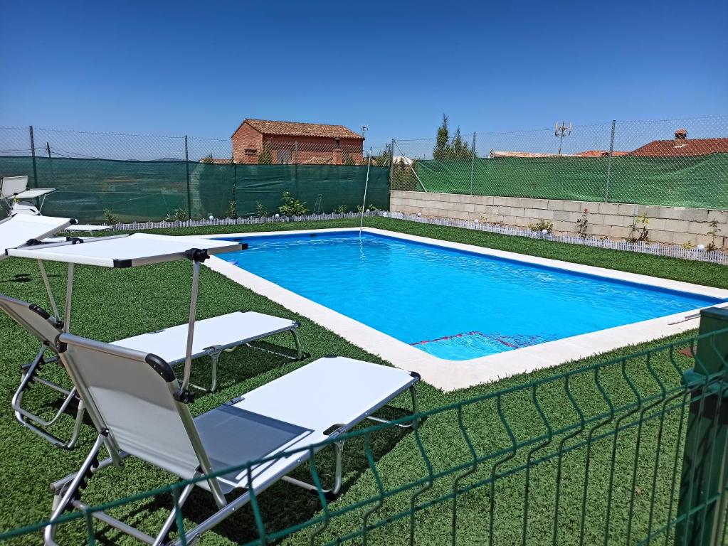 a swimming pool with two lawn chairs and a fence at LA PUERTA DE LA SIERRA in Génave