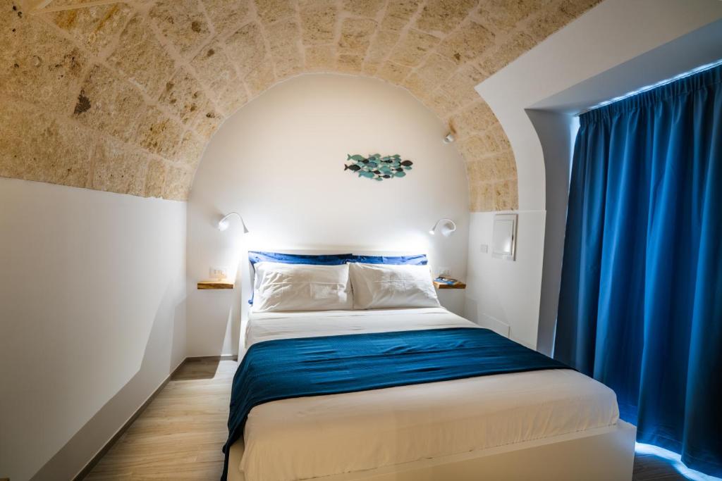 een kleine kamer met een bed met een blauw gordijn bij Vico Blu in Polignano a Mare