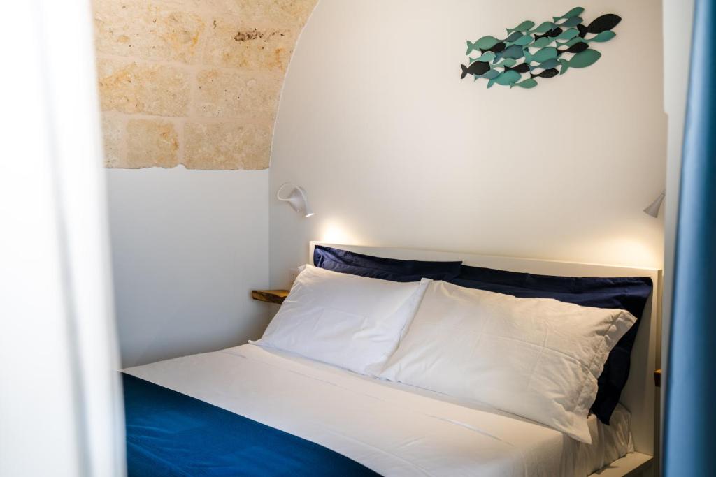 a bed with white sheets and blue pillows in a room at Vico Blu in Polignano a Mare