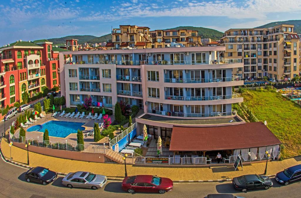 a building with a pool and cars parked in a parking lot at Anthony Complex in Sveti Vlas