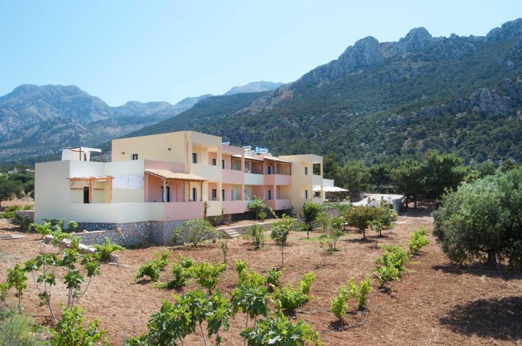 a house in a vineyard with mountains in the background at Miraluna Aparthotel in Lefkos Karpathou