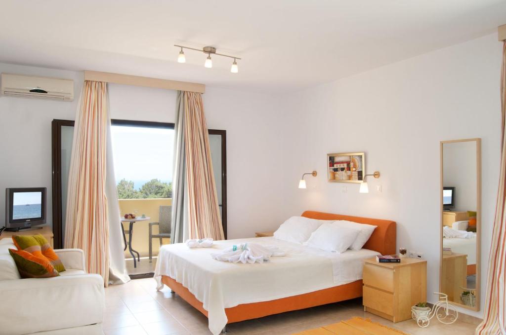 a bedroom with a large white bed and a couch at Miraluna Aparthotel in Lefkos Karpathou