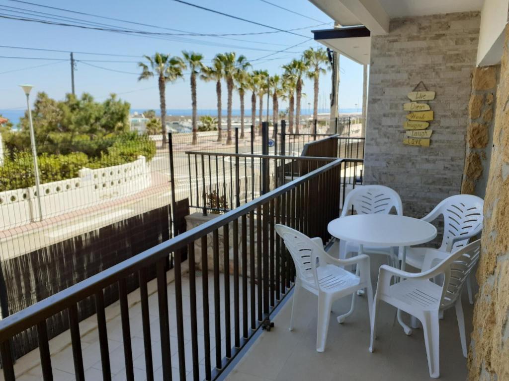 balcón con mesa, sillas y palmeras en Apartamentos Dins Mar Apto. 1 en Torredembarra