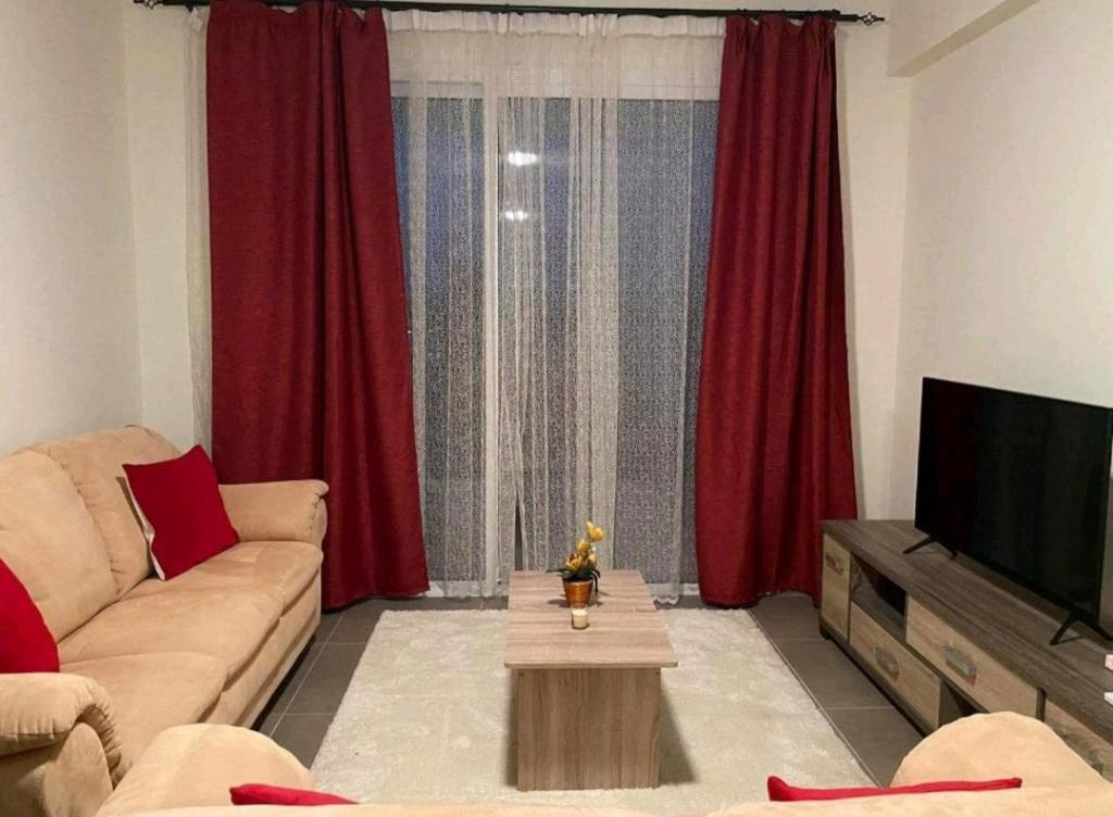 a living room with a couch and a tv and red curtains at Polis Chrysochous Apartment in Polis Chrysochous