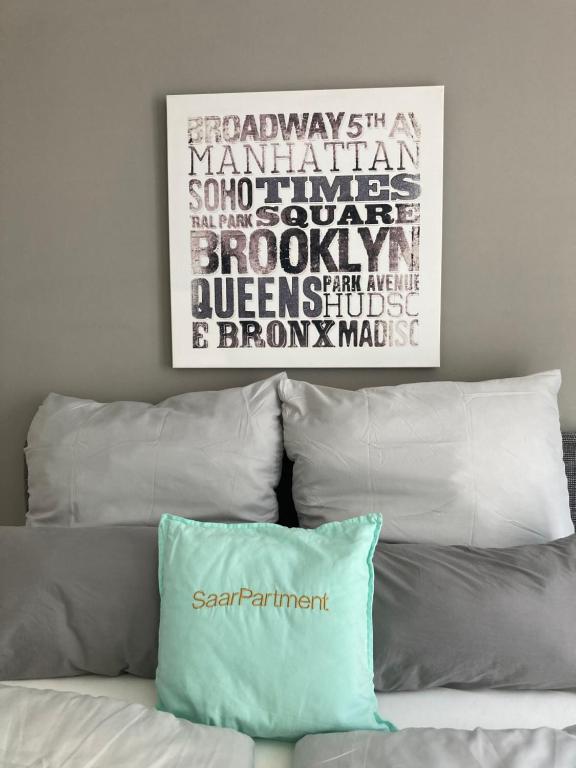 a pillow sitting on top of a bed with a painting at Living at Saarpartments - AdultsOnly - Business & Holiday Homes with Kitchen for Long- and Short Term stay, 3 min to St Johanner Markt and Points of Interest in Saarbrücken
