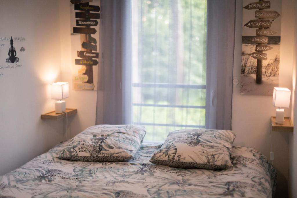 a bed with two pillows in front of a window at Appartement T1bis centre ville Andernos Les Bains in Andernos-les-Bains