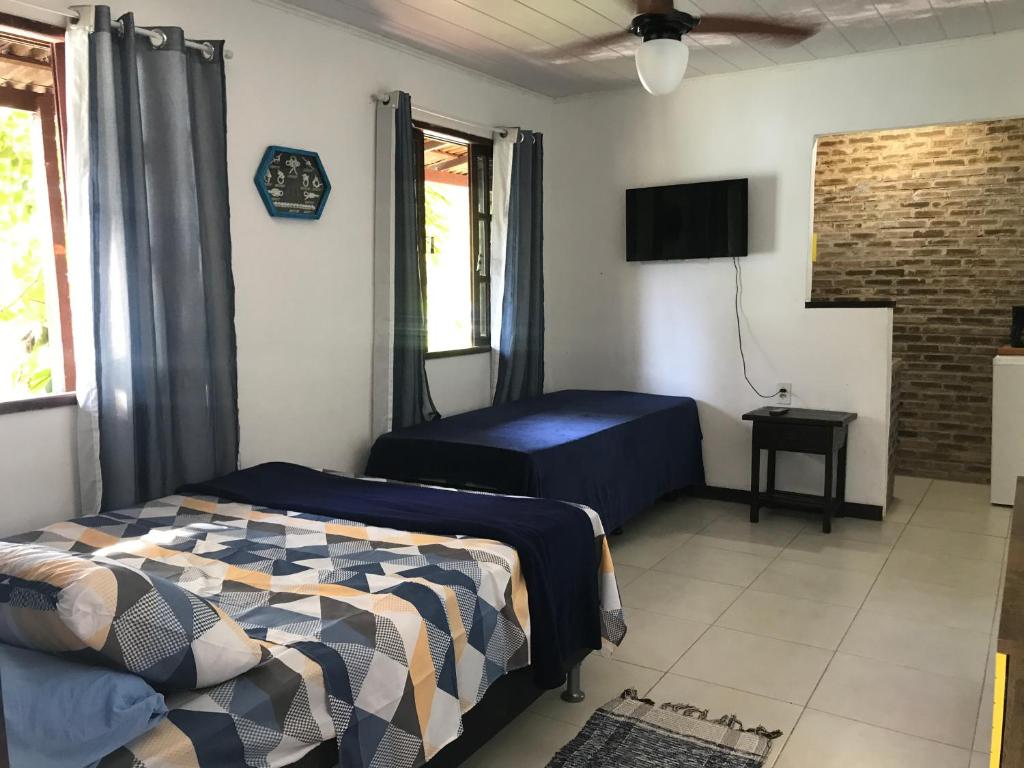 a bedroom with a bed and a flat screen tv at Praia Comprida Flats in Abraão