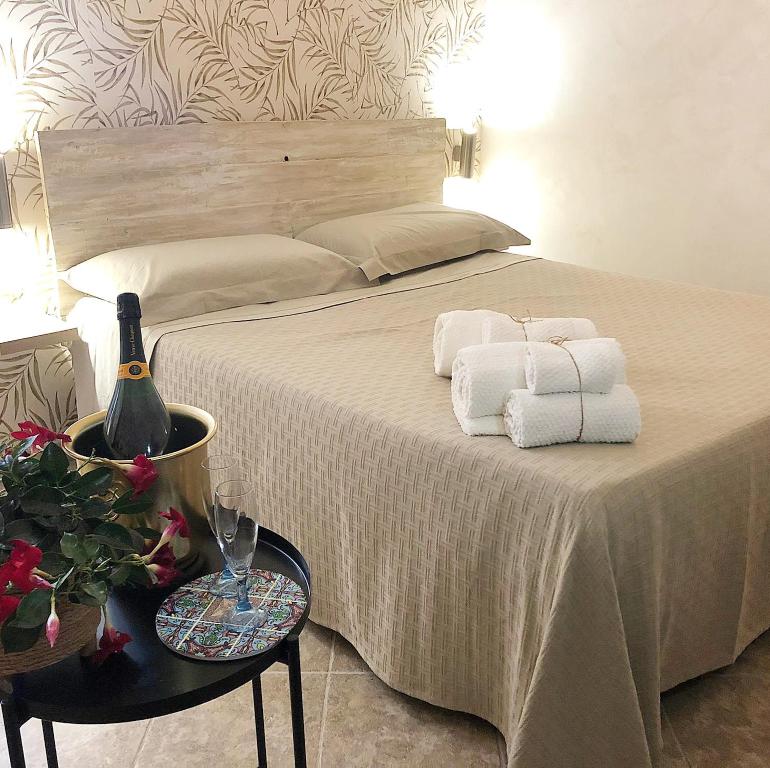 ein Bett mit Handtüchern, einer Flasche Wein und einem Tisch in der Unterkunft B&B PIETRA VIVA in Sannicandro di Bari