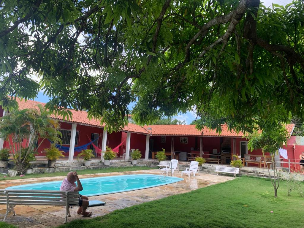 a woman sitting on a bench next to a swimming pool at CASA LAGOA DO BANANA/CUMBUCO in Caucaia