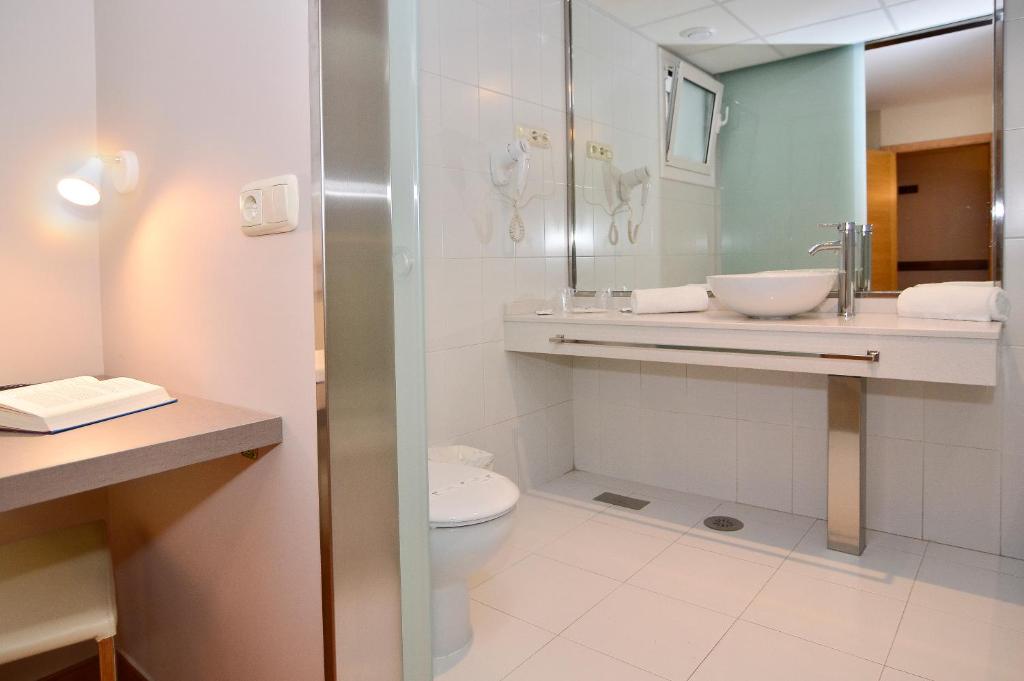 a bathroom with a toilet and a sink and a mirror at Hotel Jucamar in Cangas de Morrazo