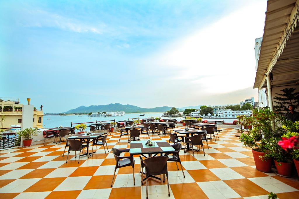 um restaurante com mesas e cadeiras num piso de xadrez em Hotel Devraj Niwas on Lake Pichola em Udaipur