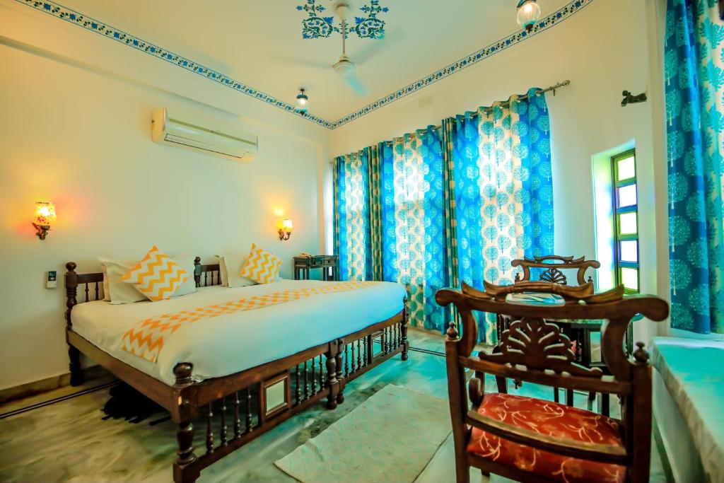 een slaapkamer met een groot bed en blauwe gordijnen bij Hotel Devraj Niwas on Lake Pichola in Udaipur